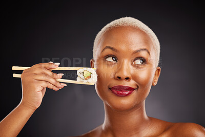 Buy stock photo Woman, thinking and sushi with chopsticks in studio for healthy eating, beauty and food. Face of a black female model with makeup on a dark background for wellness, diet or seafood advertising idea