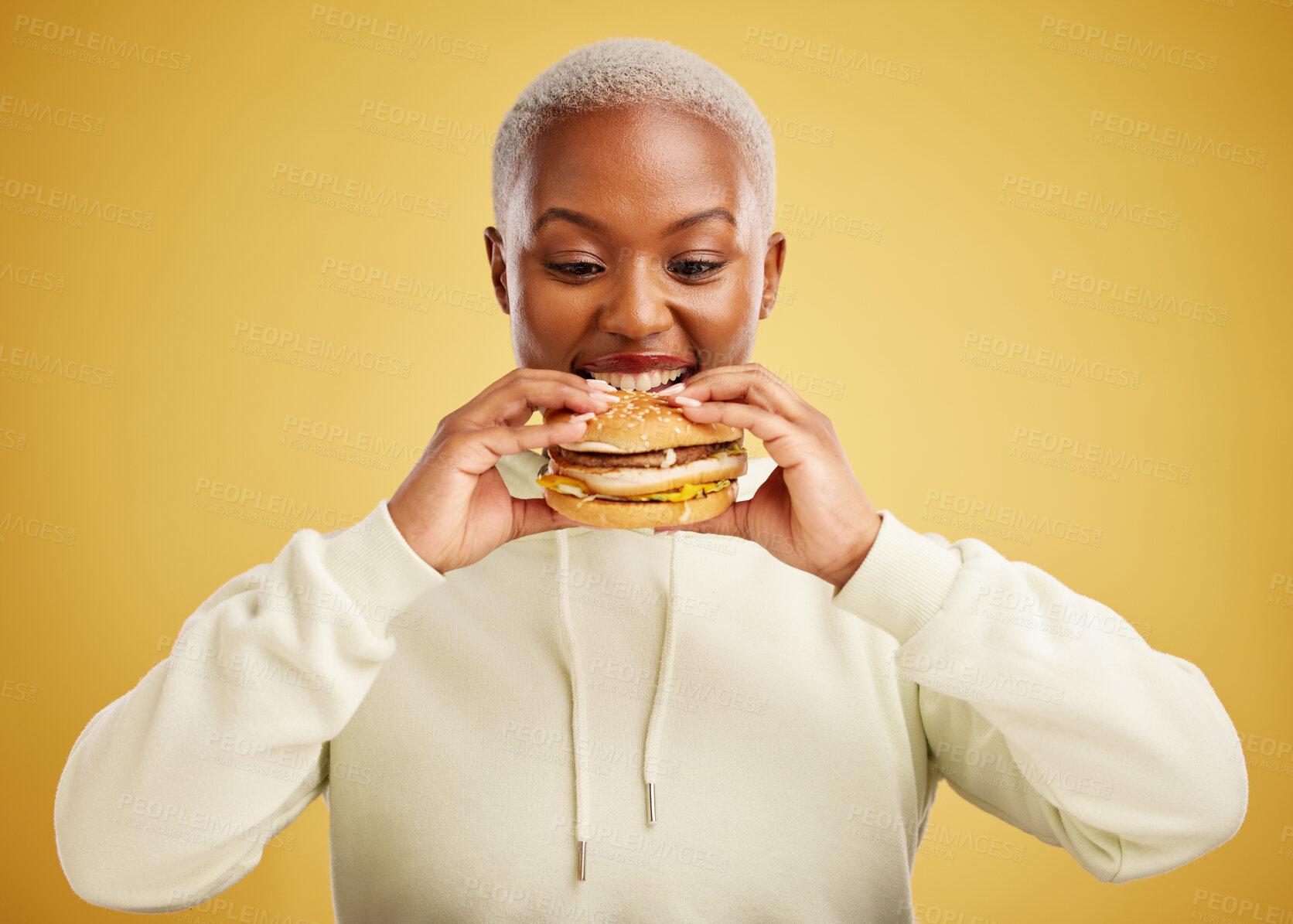 Buy stock photo Burger, eating and woman or happy student on a studio, yellow background for restaurant promotion or deal. Hungry and excited african person or customer experience with fast food and hamburger bite