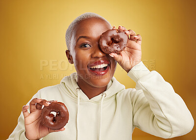 Buy stock photo Portrait, chocolate and donut with a black woman in studio on a gold background for candy or unhealthy eating. Smile, food and baking with a happy young female person holding sweet pastry for dessert