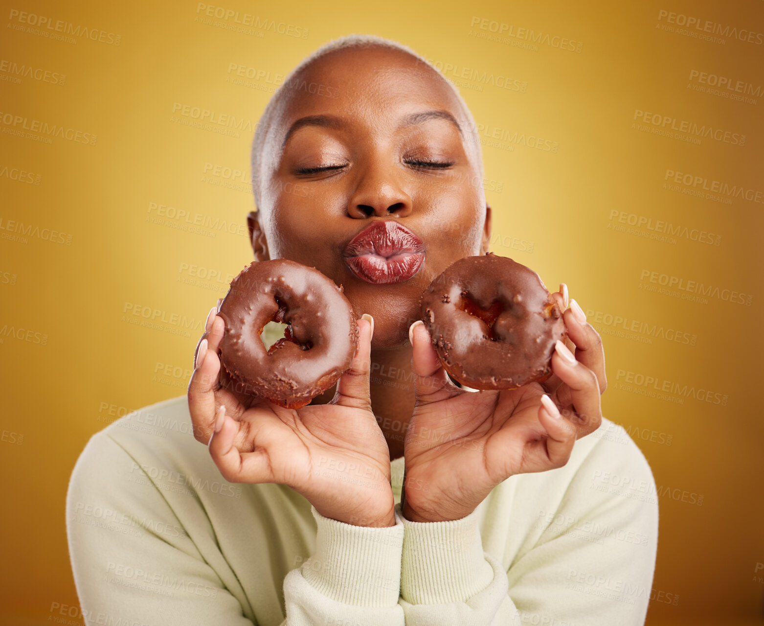 Buy stock photo Sweets, smile and black woman with donuts, funny and happiness with expression, crazy or silly. Female person, dessert or goofy model with facial, chocolate or sugar against a brown studio background