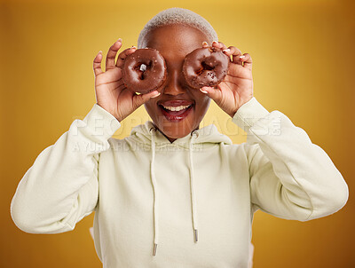 Buy stock photo Face, chocolate and donut with a black woman in studio on a gold background for candy or unhealthy eating. Smile, food and baking with an excited young female person holding sweet pastry for dessert