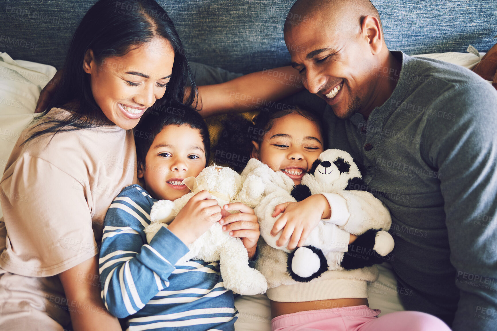 Buy stock photo Parents, children and family in a bed together with love, care and security for comfort. Woman, man and kids with a teddy bear and happy smile for quality time in a home bedroom to relax from above