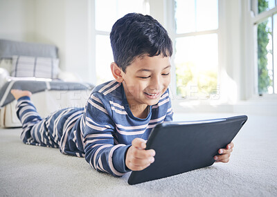 Buy stock photo Young boy, tablet and games or cartoon streaming online with internet, e learning and relax on carpet in house. Watch animation film, male kid at home and connection, entertainment and subscription