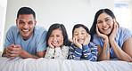Happy family, portrait and kids with parents on a bed relax, excited and bonding in their home. Face, smile and children with mother and father in bedroom for weekend, chilling and waking up playful
