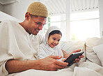 Family, tablet or study with a father and muslim girl on a sofa in the living room of their home together for e learning. Kids, education or child development with a man teaching his student daughter