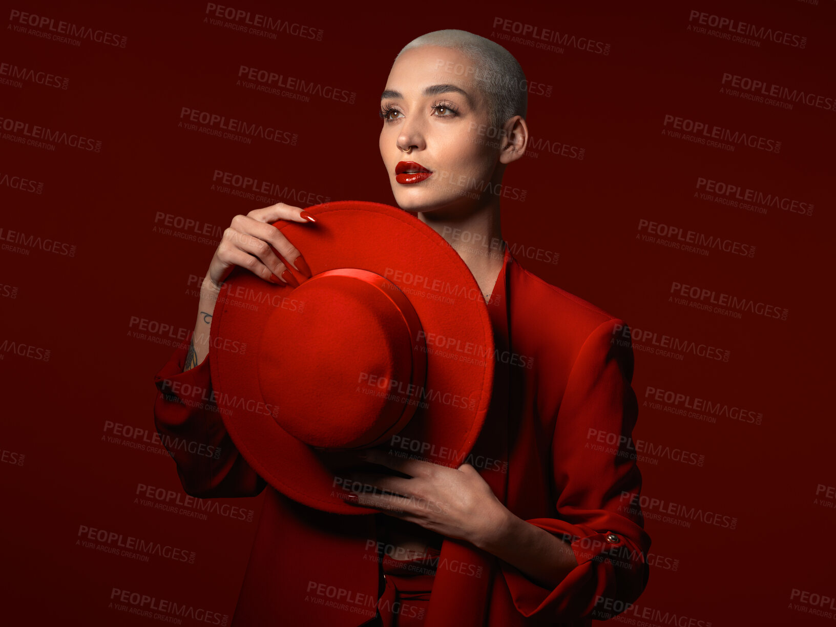 Buy stock photo Vision, fashion and hat with a woman on a red studio background for elegant or trendy style. Thinking, art and beauty with a young female person looking edgy or classy in a suit or unique clothes