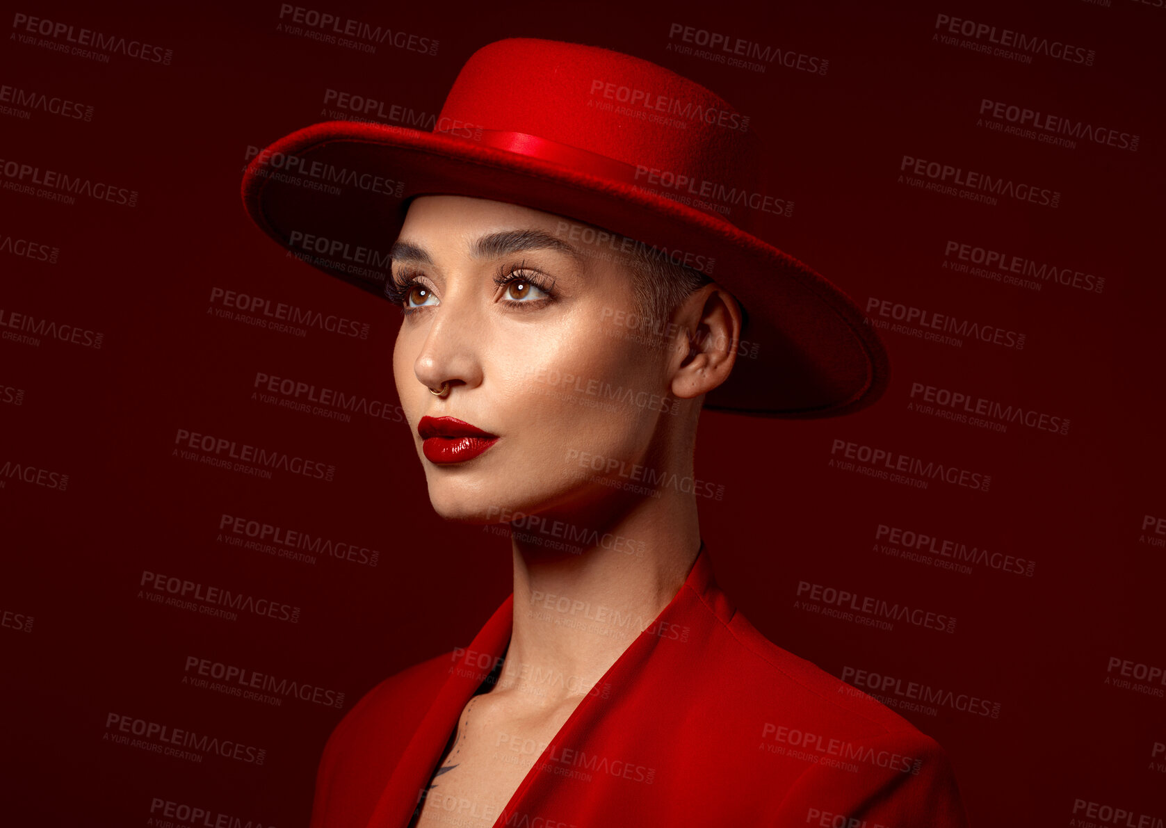 Buy stock photo Face, fashion and a model woman on a red studio background for elegant or trendy style. Vision, art and beauty with a confident young female person looking edgy or classy in a suit or unique clothes