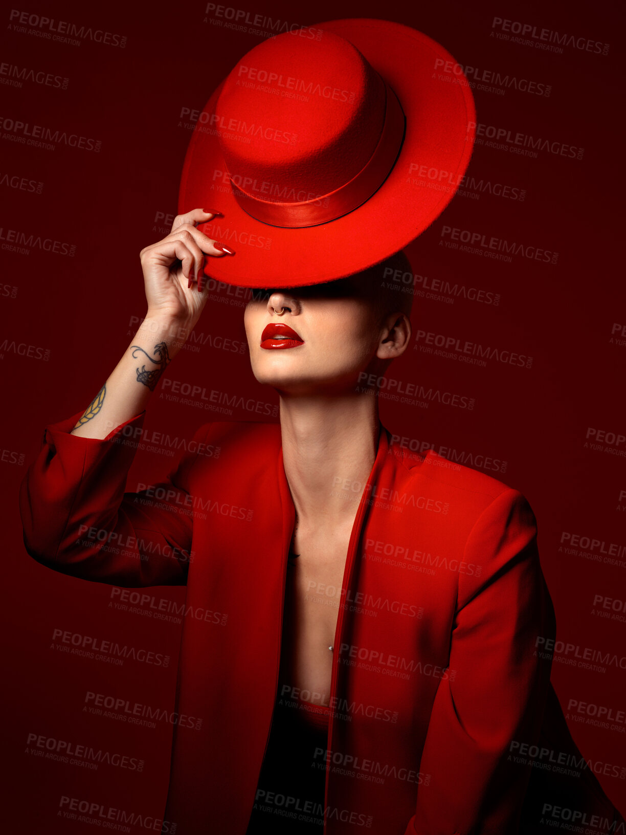 Buy stock photo Hat, fashion and a model woman on a red background in studio for elegant or trendy style. Aesthetic, art and beauty with a confident young female person posing in an edgy, classy or unique suit