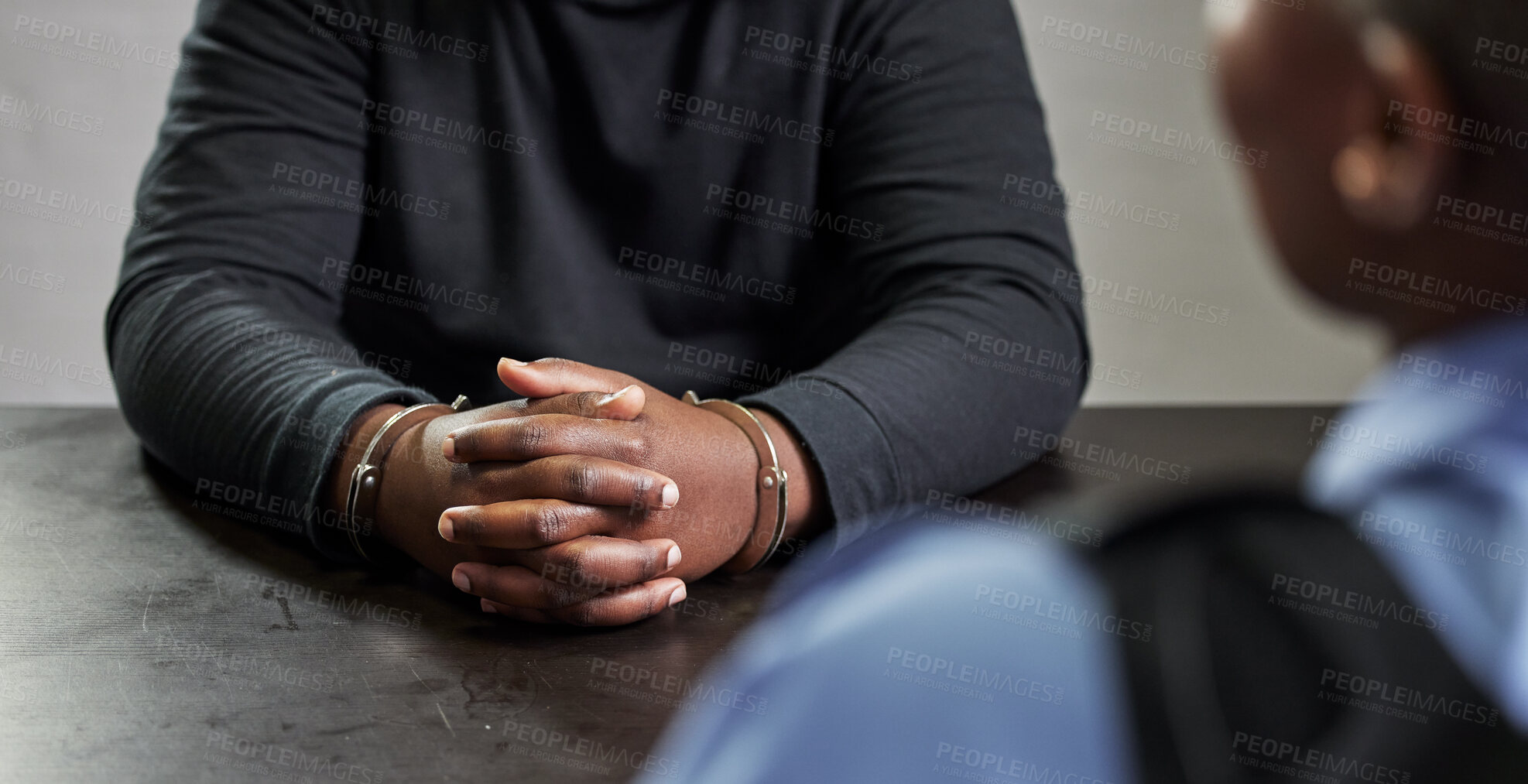Buy stock photo Criminal, hands and handcuffs and table for interrogation, questions or accusation with officer in room. Police talking to prisoner, gangster or thief for security, discussion or arrest in prison