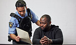 Policeman, criminal and handcuffs with documents for interrogation, question or arrest in fraud, scam or crime. Law enforcement officer talking to prisoner or thief with paperwork in prison or jail
