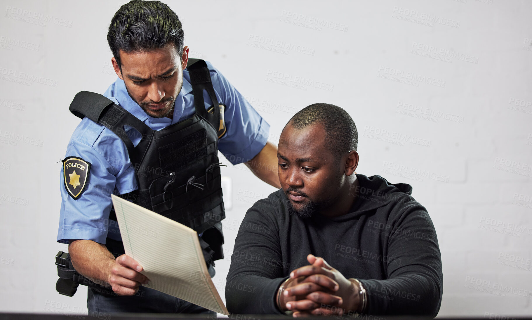 Buy stock photo Policeman, criminal and handcuffs with documents for interrogation, question or arrest in fraud, scam or crime. Law enforcement officer talking to prisoner or thief with paperwork in prison or jail