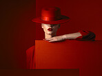 Hat, fashion and mockup with a woman on a red background in studio for marketing, advertising or branding. Luxury, aesthetic style or a trendy young female person standing with empty poster space