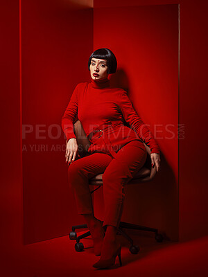 Buy stock photo Beauty, fashion and woman on a chair with red background in studio for elegant, chic or trendy style. Aesthetic, art and confident with edgy or classy young person in unique clothes or suit at board