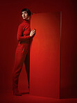 Beauty, fashion and a model woman on red background in studio for elegant, chic or trendy style. Aesthetic, art and confident with an edgy or classy young person in a unique clothes or suit at board