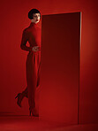 Fashion, mockup and a model woman in a red background in studio for marketing, advertising or branding. Luxury, aesthetic style or a trendy young female person standing with an empty or blank poster
