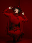 Woman, fashion and beauty with red aesthetic, makeup with art deco and vintage hat isolated on studio background. Retro style, female model with serious expression and cosmetics, attractive and bold