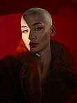 Portrait, fashion and serious woman in red coat in studio isolated on a background. Face, makeup and bald female model with cosmetics, aesthetics or stylish, trendy or classy clothes from Switzerland
