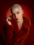 Portrait, fashion and confident woman in a red coat in studio isolated on a background. Face, makeup and serious bald model with cosmetics, aesthetic or stylish, trendy and clothes from Switzerland