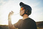 Biker, drinking water and man with helmet and sunglasses outdoor in nature for sports training workout. Sky, thirst or wellness of male person with hydration for off road cycling, travel or adventure