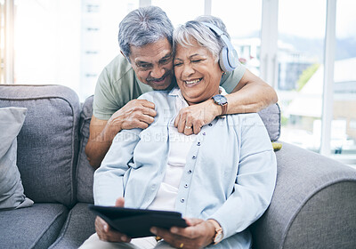Buy stock photo Senior, hug and couple with a tablet for a website, streaming music in home living room. Laughing, sofa and an elderly man and woman with a movie or funny video on technology or listening together