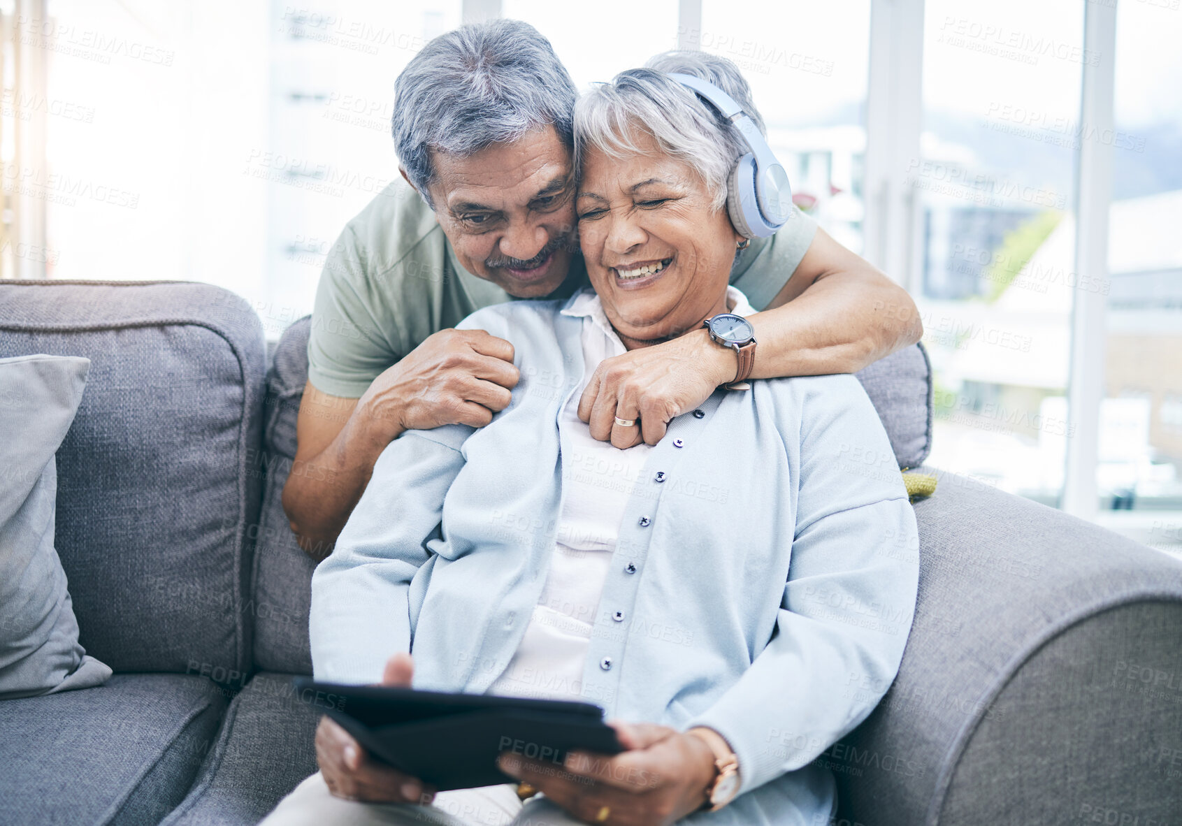 Buy stock photo Senior, hug and couple with a tablet for a website, streaming music in home living room. Laughing, sofa and an elderly man and woman with a movie or funny video on technology or listening together
