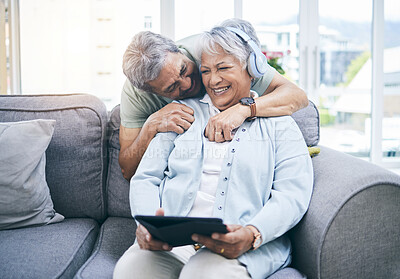 Buy stock photo Laughing, hug and couple with a tablet for a website, streaming music or a podcast together. Love, embrace and a senior man and woman with a movie or funny video on technology or listening to audio