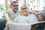 Couple, talking and reading book together on sofa in living room with love, relax and quality time. Senior man, happy woman or partner with glasses, discussion or books on couch at home in retirement