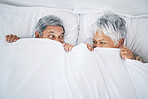 Bed, funny and senior couple playing together in a bedroom bonding as care, happiness and relax to enjoy retirement. Happy, goofy and elderly people, man and woman with trust in marriage in a home