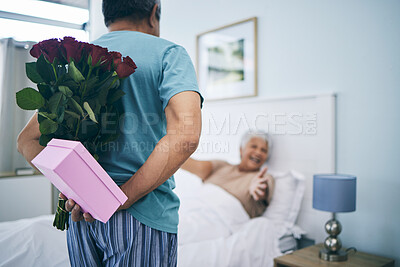Buy stock photo Gift, surprise and a senior couple on their anniversary in the bedroom of their house together for celebration in the morning. Flowers, birthday box and an old man giving his wife a present at home