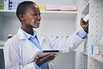 Black woman, pharmacist and tablet at medicine shelf for stock check in pharmacy, drugstore or shop. Medical professional, inventory and happy doctor with tech, pills or supplements for healthcare.