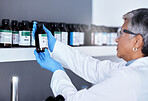 Laboratory, science and woman with bottle from shelf to check medical research information. Healthcare, medicine and innovation in manufacturing of vaccine or prescription drugs with senior scientist