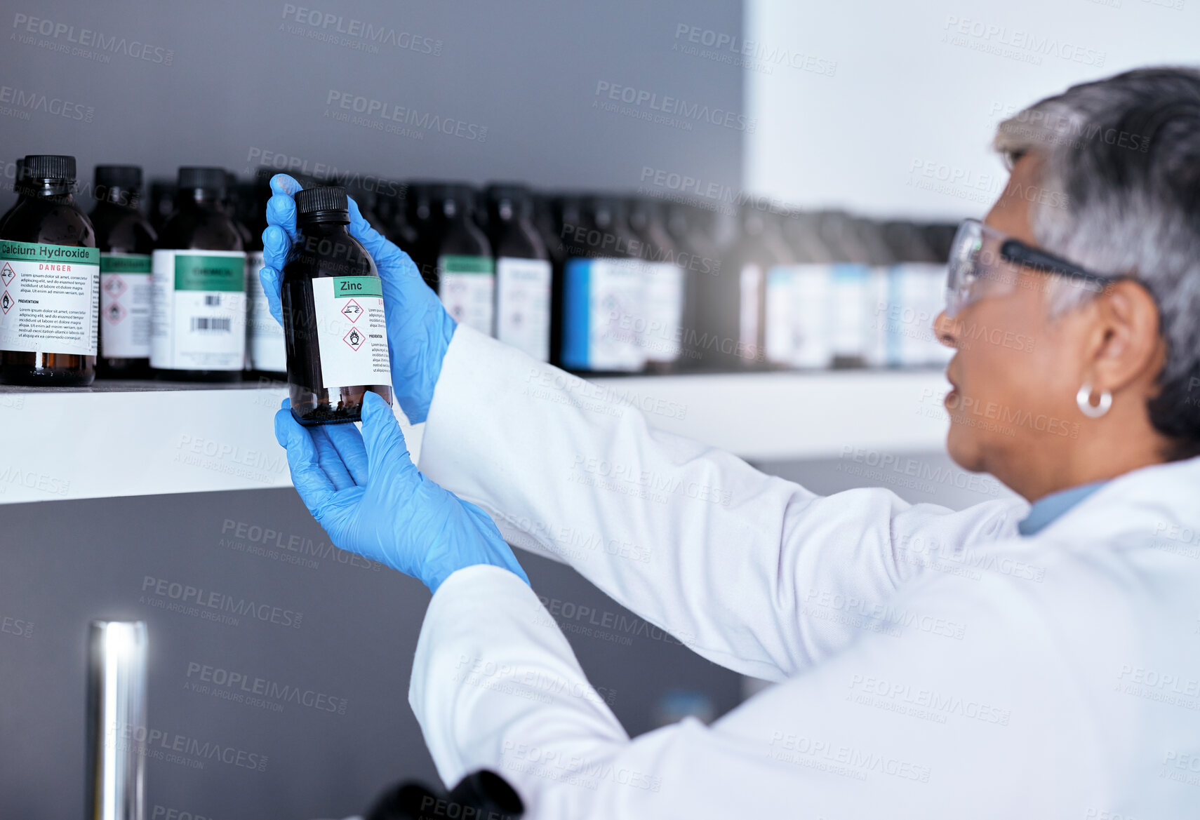 Buy stock photo Laboratory, science and woman with bottle from shelf to check medical research information. Healthcare, medicine and innovation in manufacturing of vaccine or prescription drugs with senior scientist