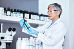 Lab, science and woman checking bottle from shelf for medical research information and solution. Healthcare, medicine and innovation in manufacturing vaccine or chemical drugs with senior scientist.