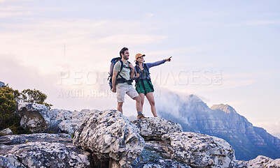 Buy stock photo Mountain, trekking and view, man with woman on peak for adventure in nature, rock climbing and travel. Outdoor hiking, couple on cliff and relax in scenic clouds for natural journey, pointing at sky.