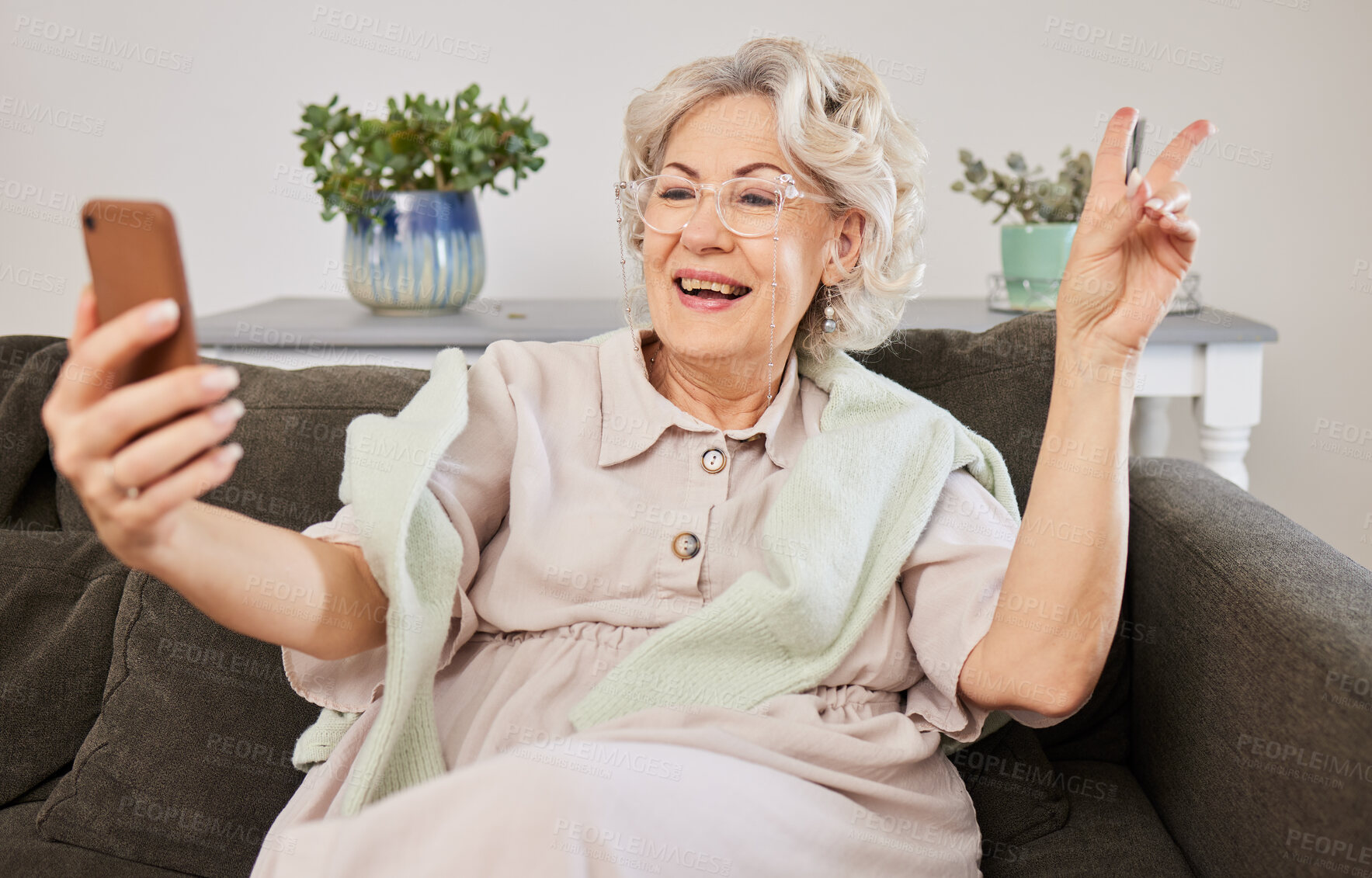 Buy stock photo Selfie, peace and a senior woman posing on a sofa in the living room of her home during retirement. Social media, profile picture and hand gesture with a happy mature female person in her house