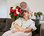 Couple kiss, senior and flowers for a birthday, love or celebration of marriage together. Happy, care and elderly man with bouquet for a woman in a house for a surprise, date or gift for anniversary