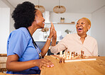 Caregiver playing chess with an elderly patient after healthcare consultation in nursing rehabilitation center. Board game, high five and female nurse bonding with senior woman in retirement home.