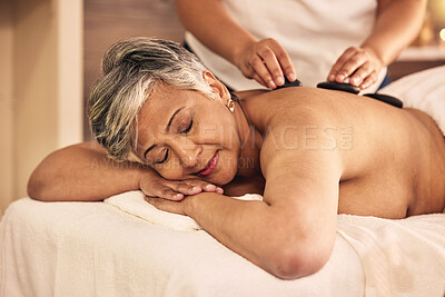 Buy stock photo Woman, spa and stone massage on back for skincare treatment, holistic therapy and stress relief at beauty salon. Mature female person relax at wellness resort with rocks to detox muscle for self care