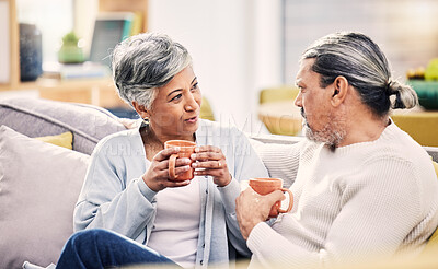 Buy stock photo Coffee, conversation and senior couple on a sofa for bond, discussion or sharing gossip in their home. Love, tea and old people relax on couch for break, speaking or did you know drama in living room