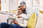 Love, hug and mature couple on a tablet networking on social media, mobile app or the internet. Happy, embrace and senior man and woman browsing on digital technology on a sofa in living room at home