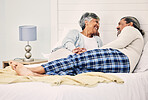 Love, relax and an elderly couple in bed together, bonding in the morning while enjoying retirement in their home. Happy, conversation and an old woman with her husband in a bedroom while on holiday