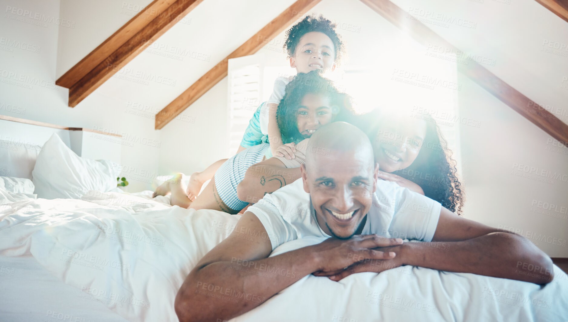 Buy stock photo Pile, family and portrait in home bedroom, bonding and sunshine with lens flare. Face, happy and children with father, mother and parents on bed with love, care and quality time for game together.