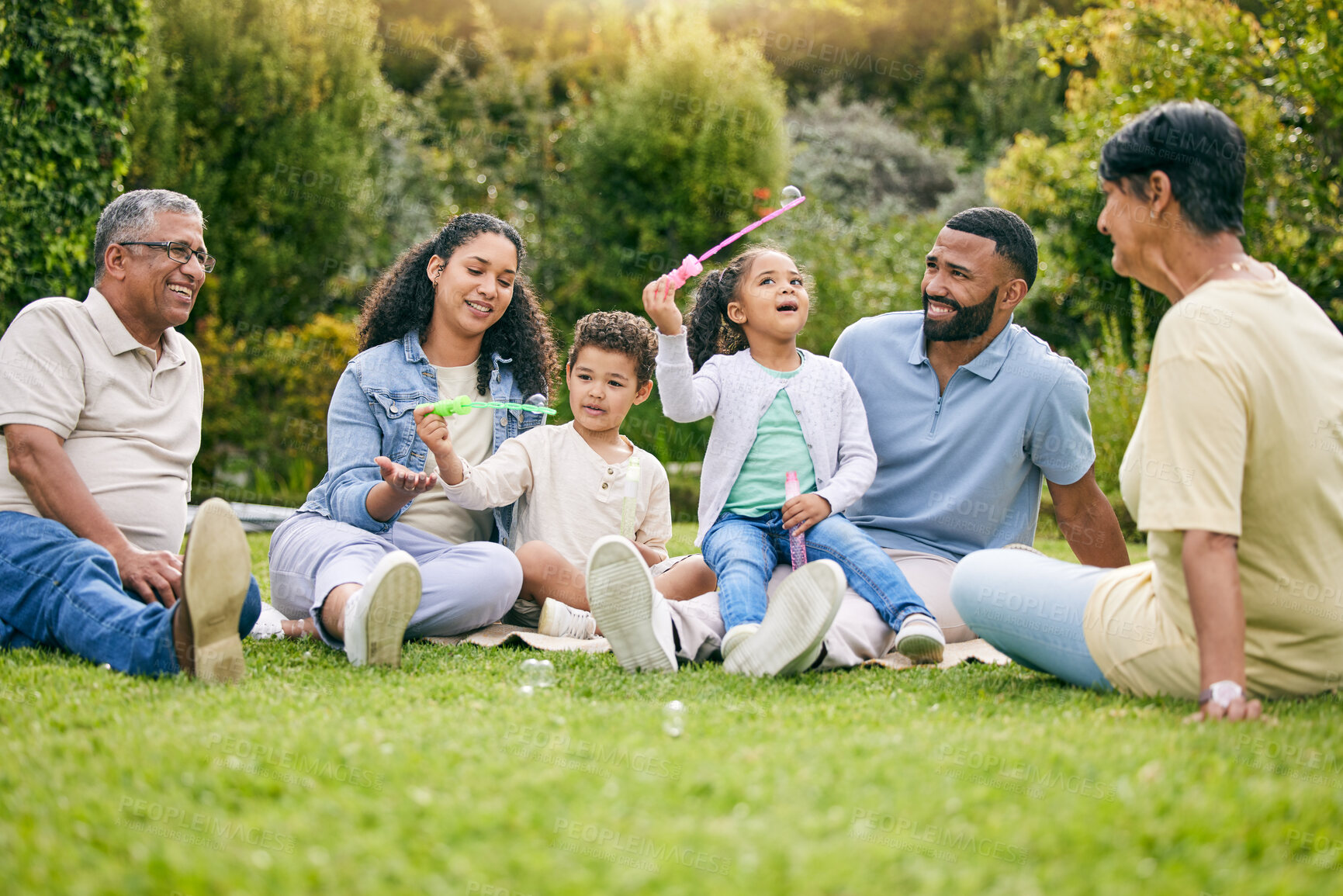 Buy stock photo Picnic, bubbles and family relax, happy or children enjoy toys, outdoor quality time together and nature garden. Summer freedom, grass field and bonding grandparents, parents and kids playing in park
