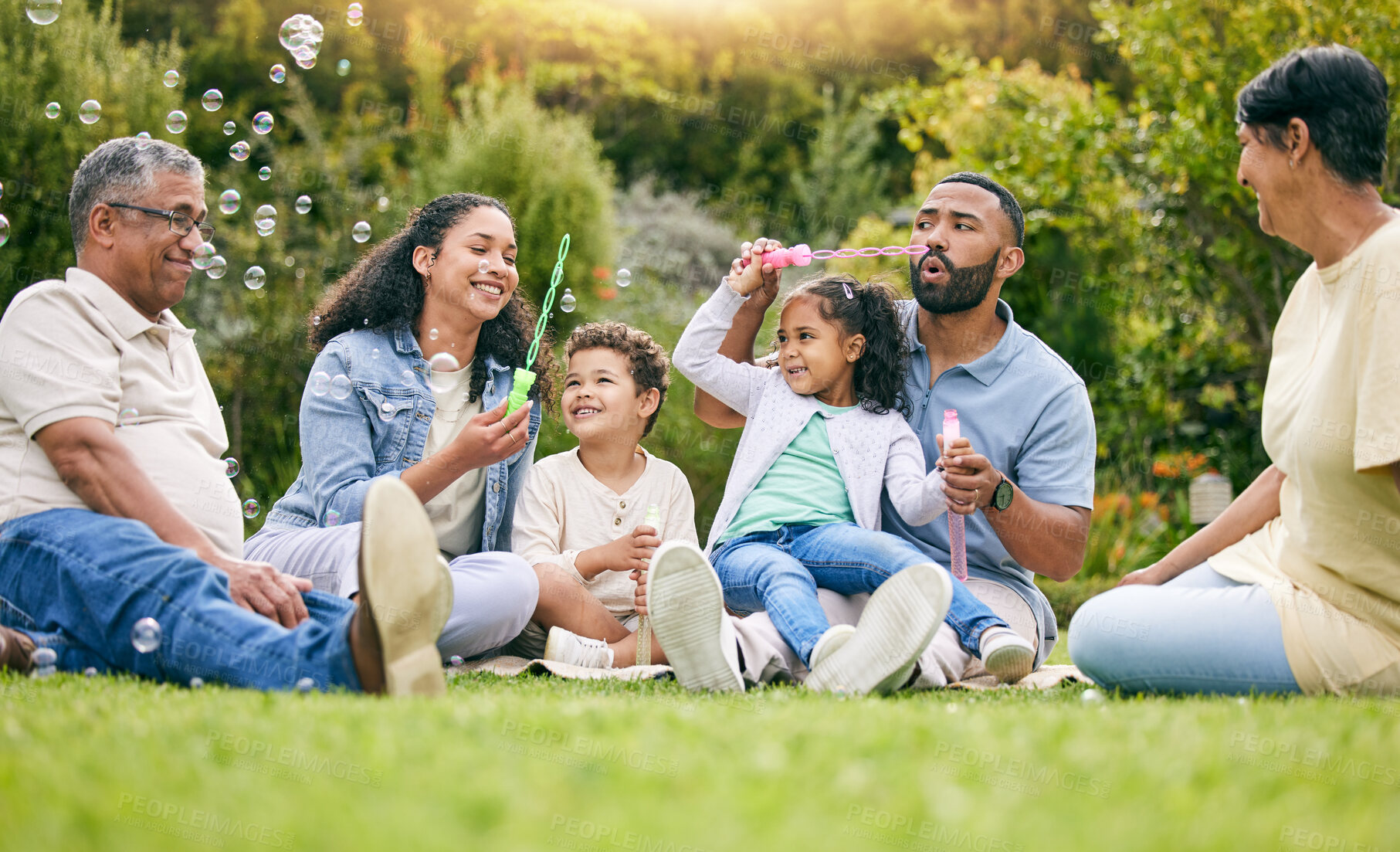 Buy stock photo Nature picnic, bubbles and happy family relax, smile or kids enjoy toys, outdoor time together and garden fun. Natural spring freedom, park games or bonding grandparents, parents and children playing