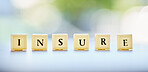 Letters, blocks and an insurance message on a desk for business, security or finance with bokeh. Office, corporate and a word on a table at a financial company for profit, investment or saving