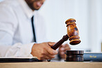 Hand, gavel and a man judge in court for order during a verdict in a criminal case or trial closeup. Justice, law or legal with a magistrate in the courtroom for a hearing of evidence or legislation