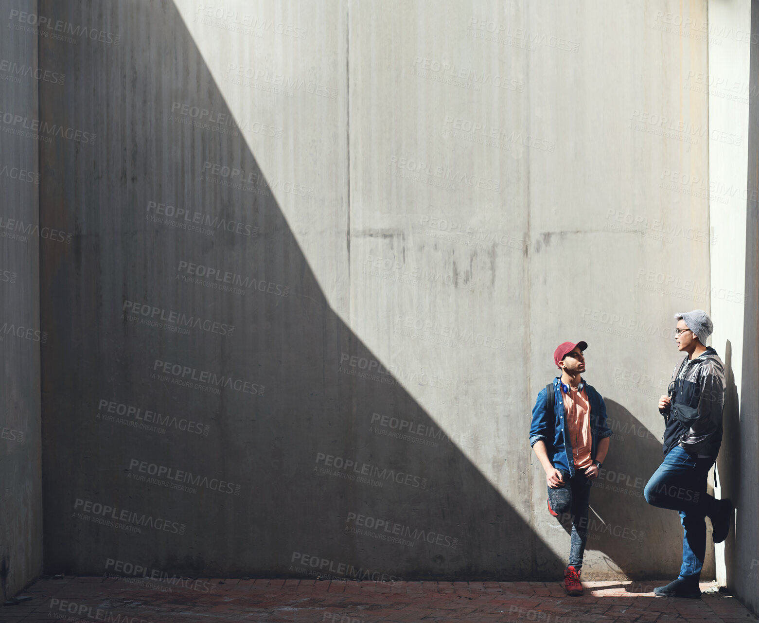 Buy stock photo Fashion, friends and men in a city talking, bond and hanging out on the weekend against wall background. Chilling, conversation and male people downtown for fun, freedom and off day with trendy style