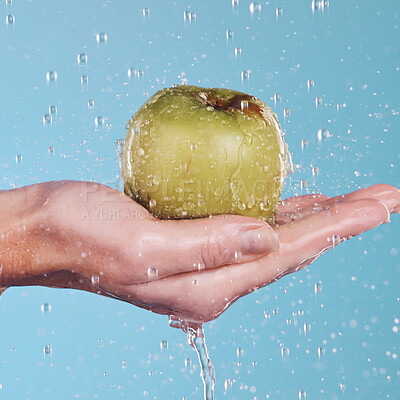 Buy stock photo Health, water and a hand with an apple on a blue background for nutrition, cleaning or wellness. Diet, food and closeup of a person with a fruit in palm for a detox isolated on a studio backdrop