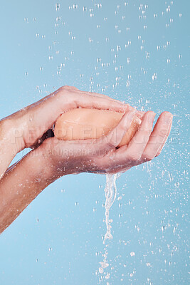 Buy stock photo Water, soap and a person washing hands in studio on a blue background for hygiene or hydration. Cleaning, wellness and skincare with an adult in the bathroom to remove bacteria or germs for health