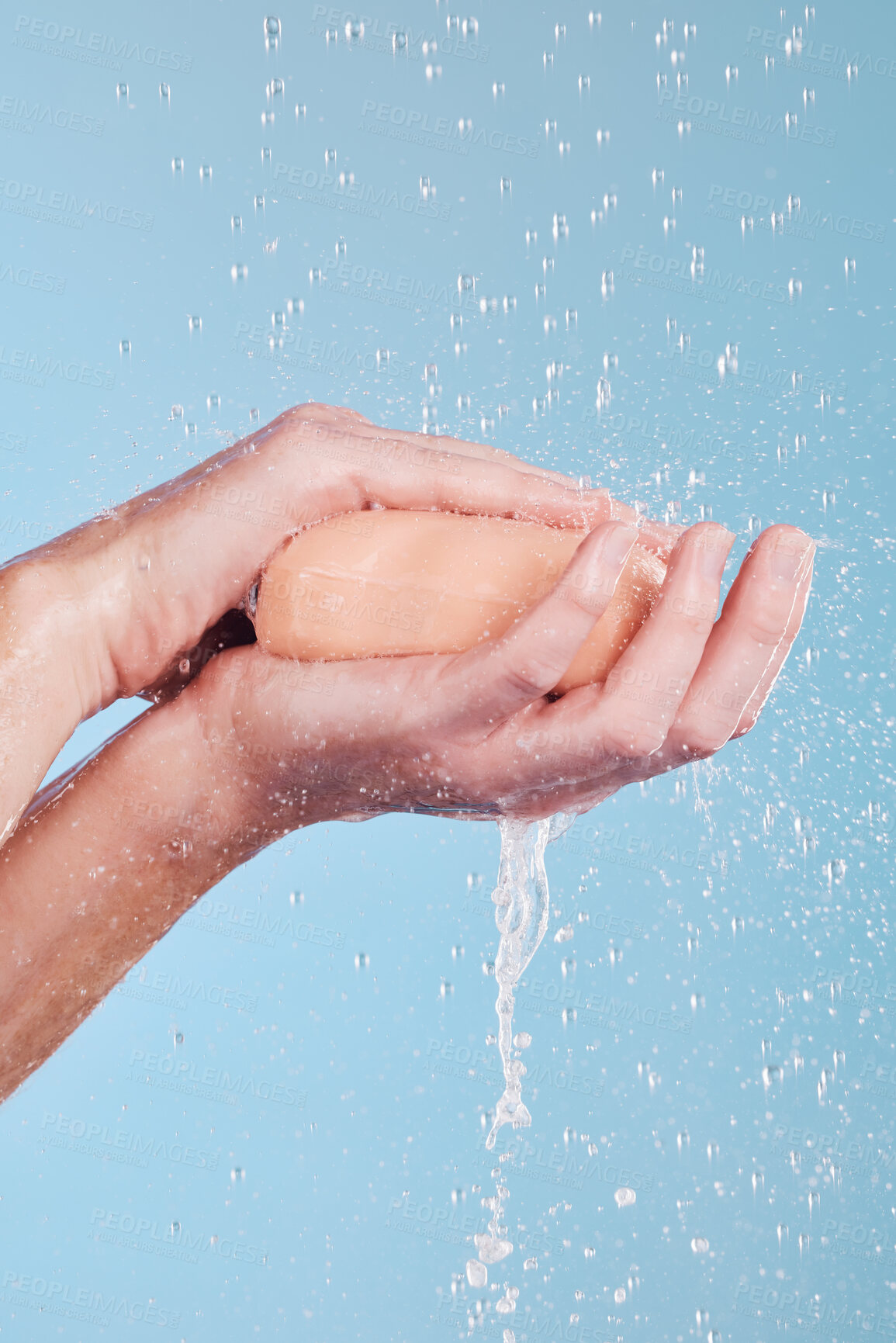 Buy stock photo Water, soap and a person washing hands in studio on a blue background for hygiene or hydration. Cleaning, wellness and skincare with an adult in the bathroom to remove bacteria or germs for health